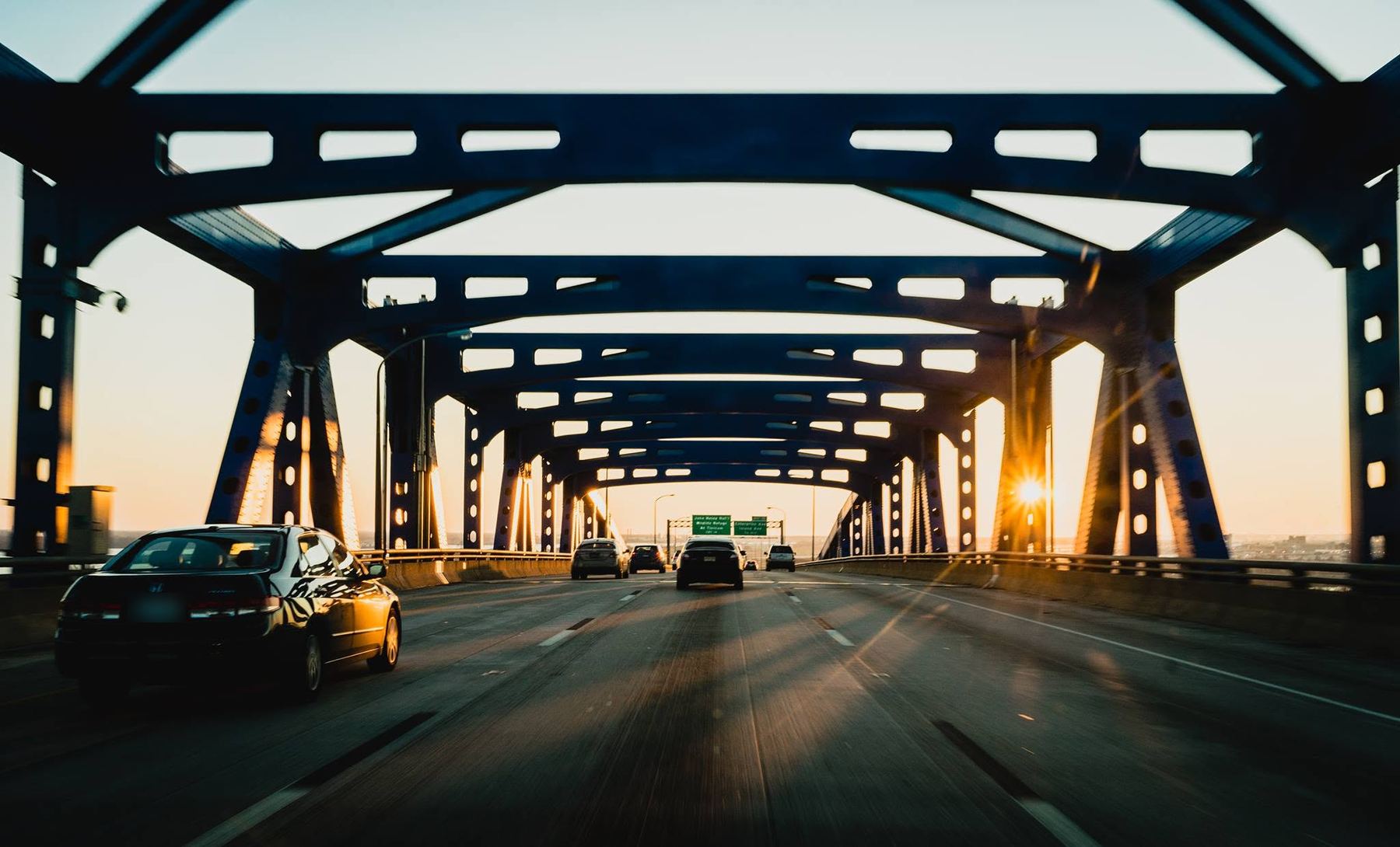 Cars crossing a steel bridge at sunset
